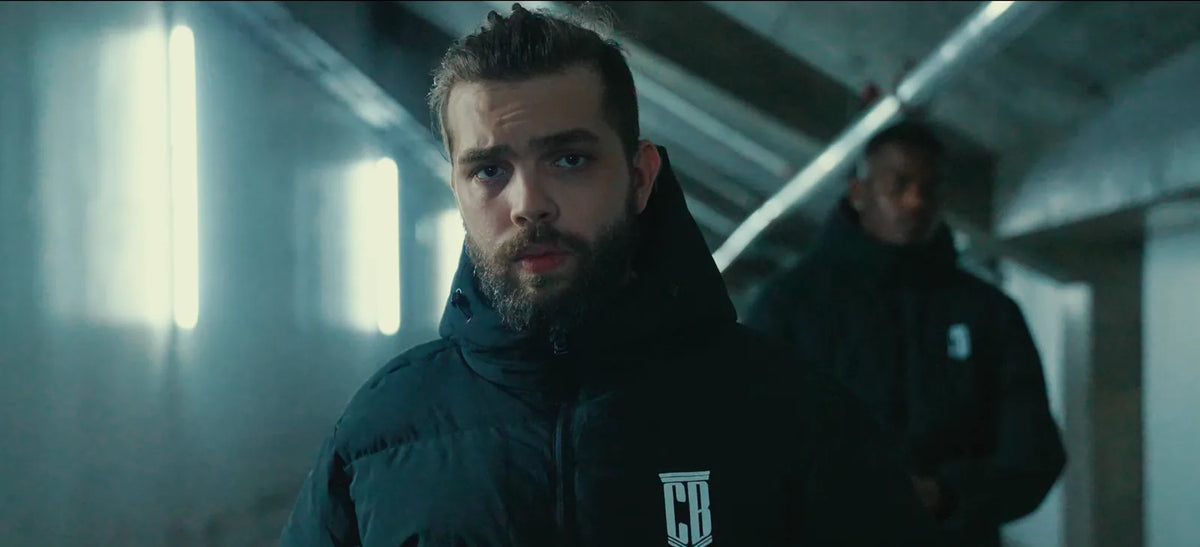 Man in a black CB puffer jacket with white CB crest, still from the Colonel Bench film