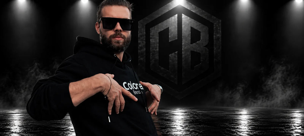 Man in a black Colonel Bench hoodie and CB Mask sunglasses, studio background